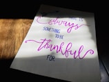 A piece of paper with a handwritten motivational quote in cursive and print styles, displayed on a wooden surface with light and shadow creating a dramatic effect.