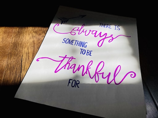 A piece of paper with a handwritten motivational quote in cursive and print styles, displayed on a wooden surface with light and shadow creating a dramatic effect.