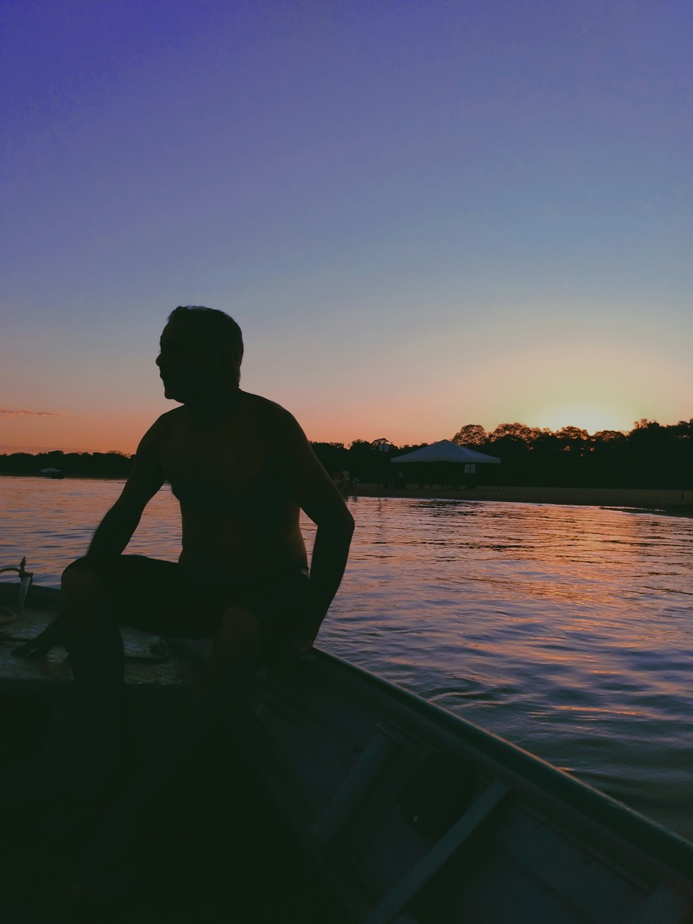 silhueta do homem sentado no barco durante o pôr do sol