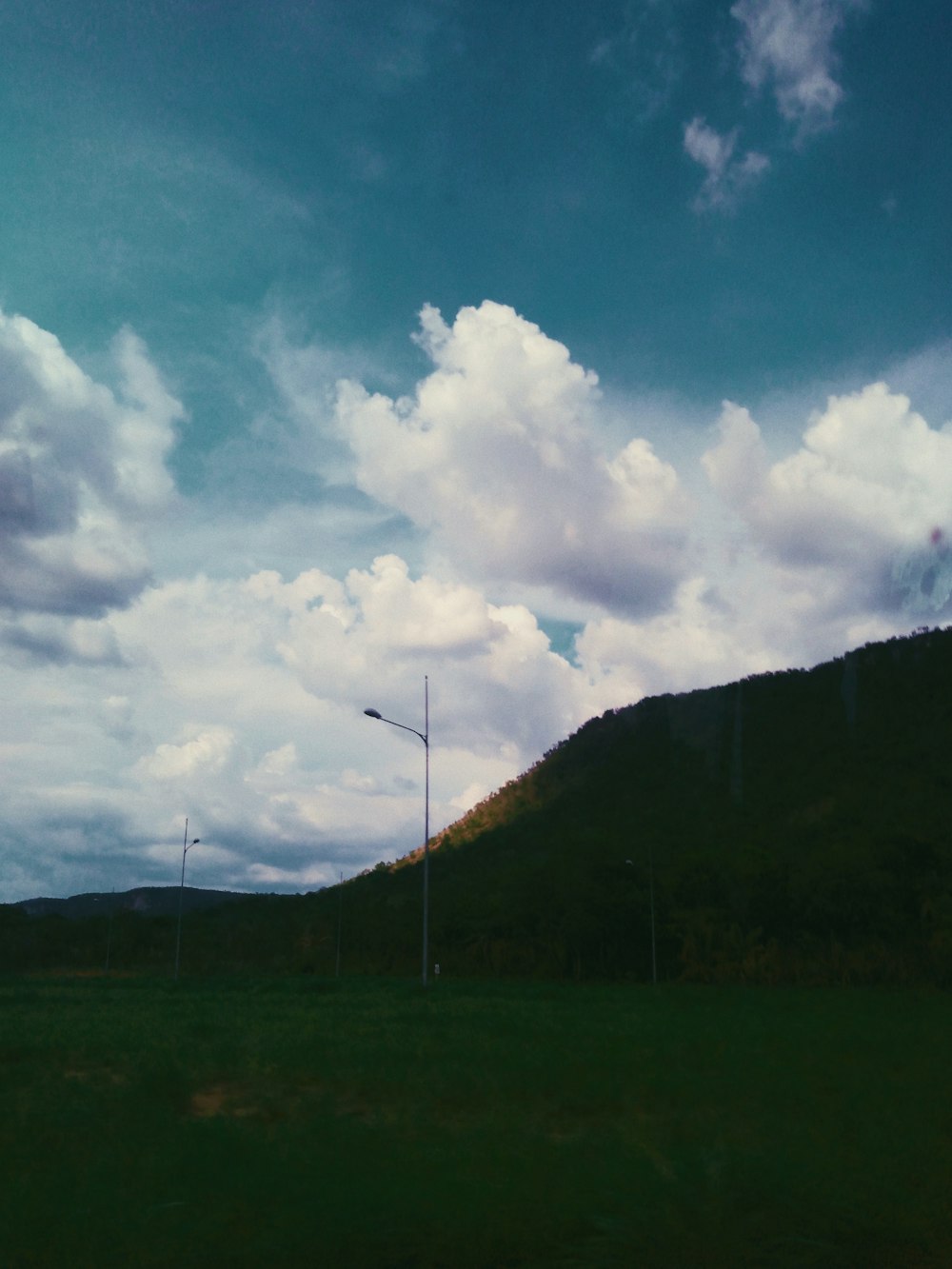 green grass field under blue sky and white clouds during daytime