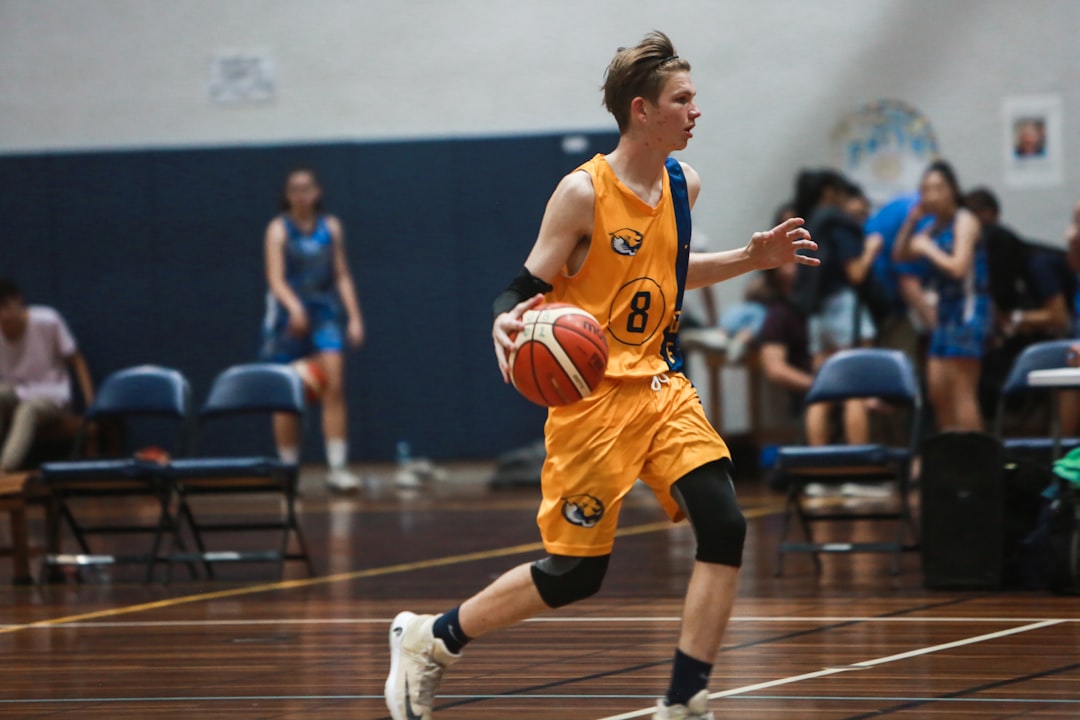 woman in orange jersey shirt playing basketball