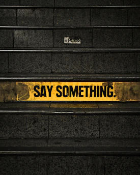 a yellow and black sign that says say something
