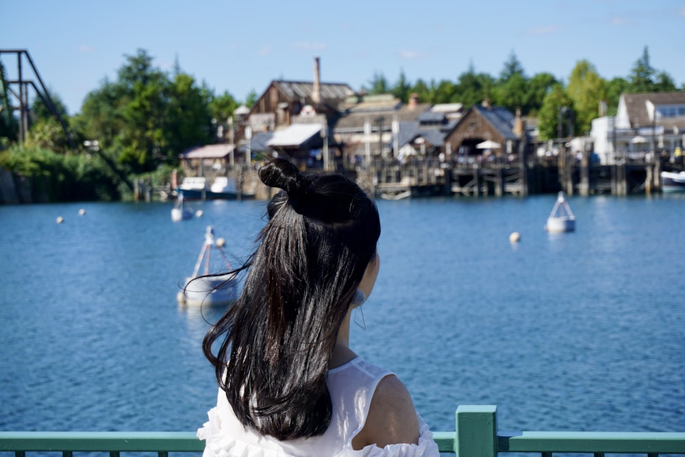 woman in white tank top sitting on bench near body of water during daytime