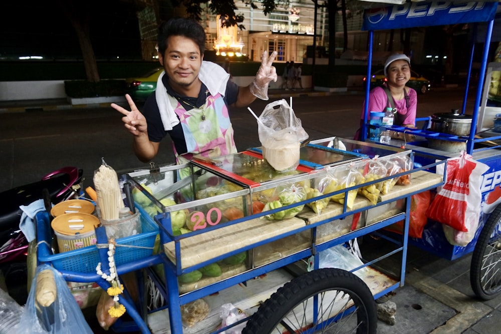 a man standing next to a cart filled with food