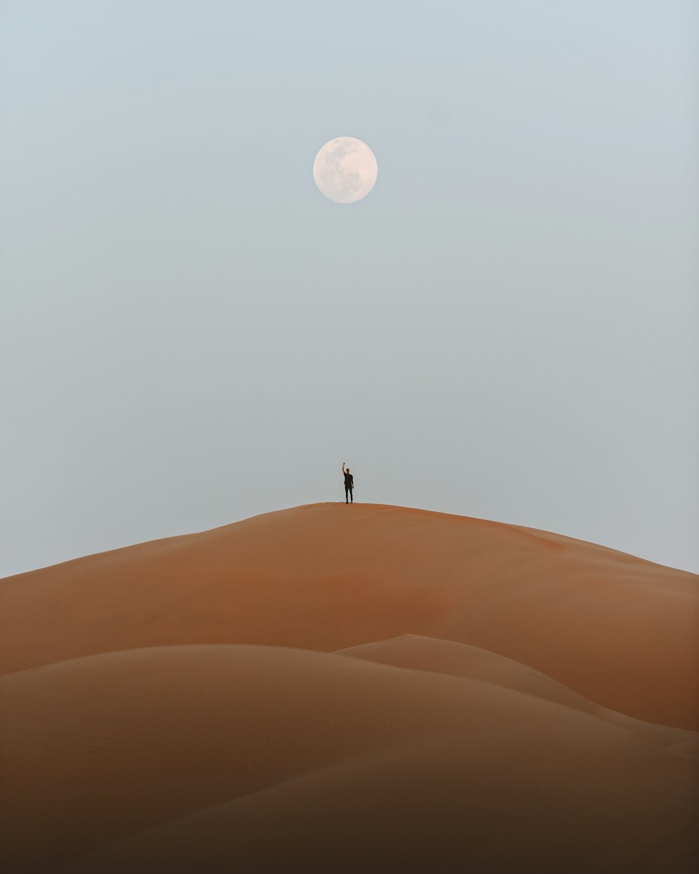 man standing on desert under full moon