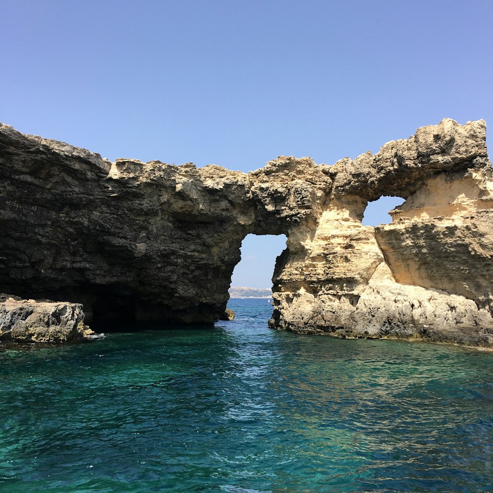 brown rock formation on blue sea under blue sky during daytime