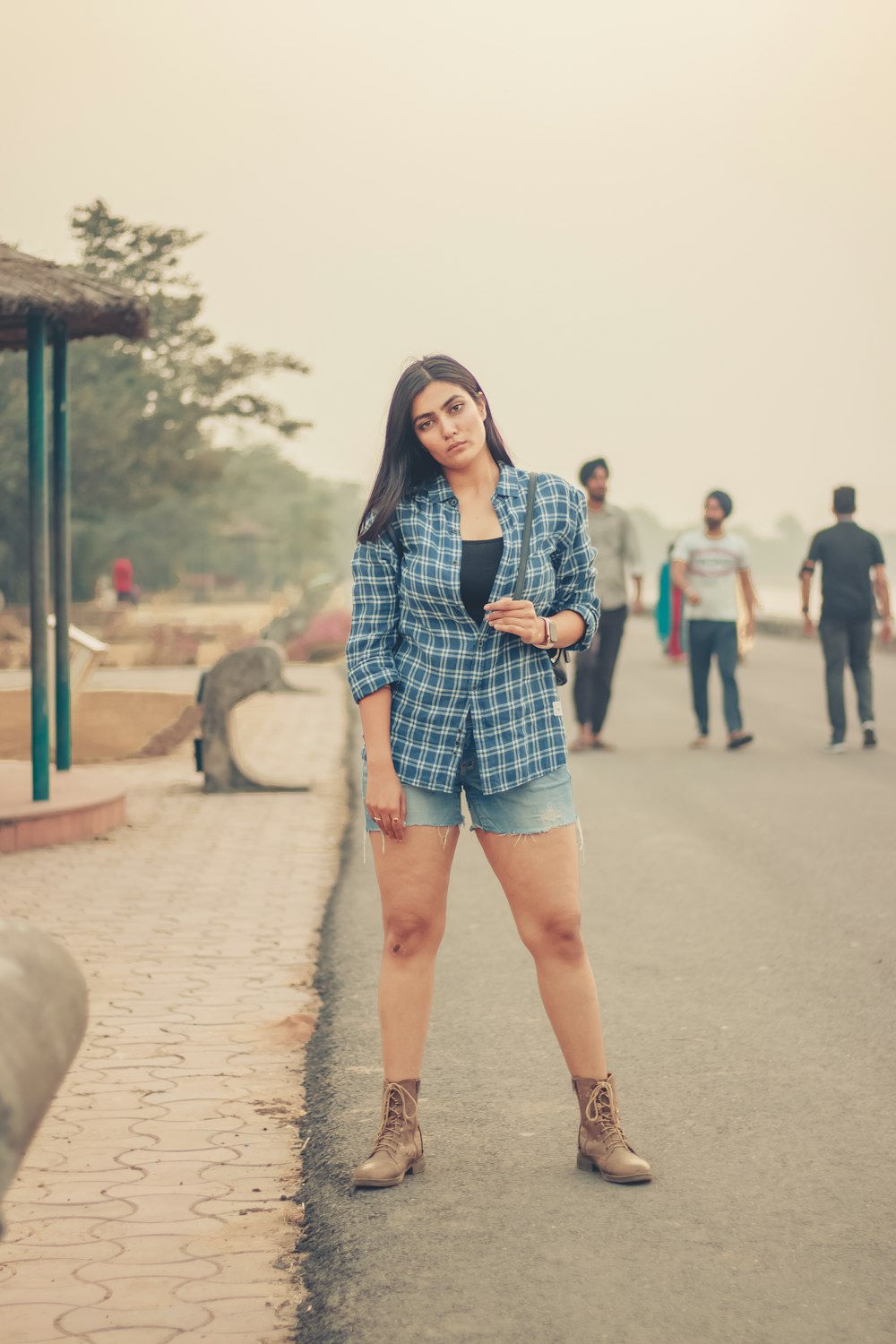 woman in blue and white plaid long sleeve shirt standing on gray concrete pavement during daytime