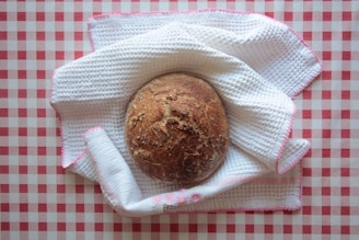 A warm, rustic loaf of bread on a black and white checkered cloth.