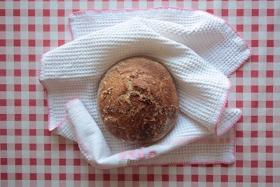 A warm, rustic loaf of bread on a black and white checkered cloth.