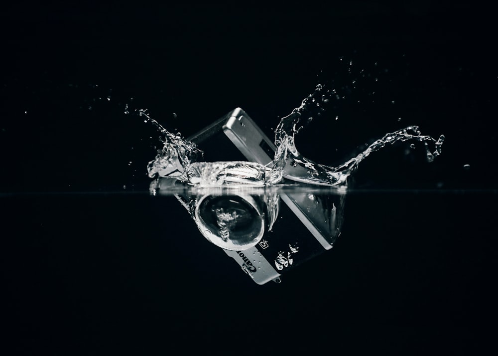 a camera splashing into the water on a black background