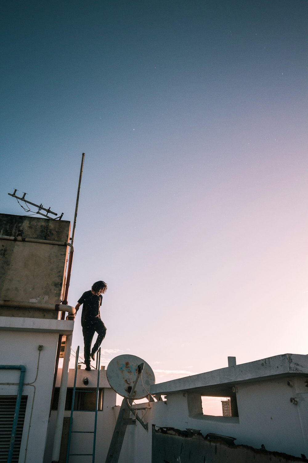 man in black jacket and pants standing on white concrete building during daytime