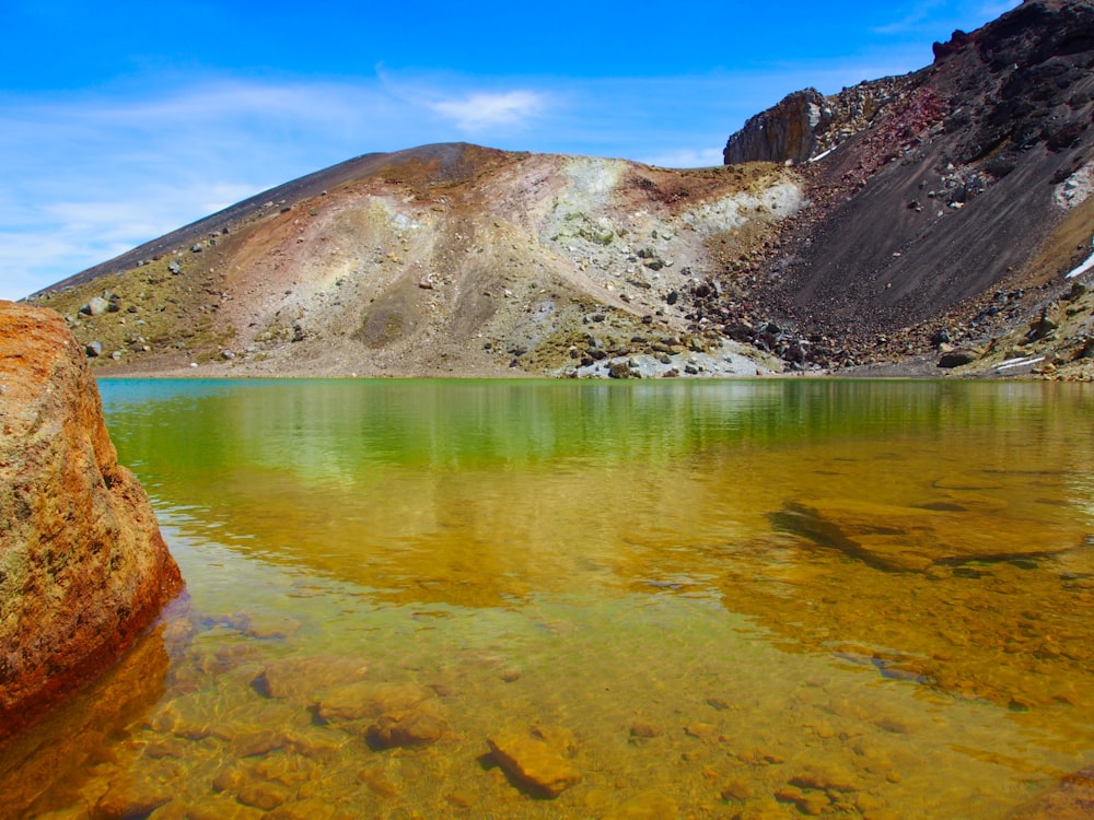 brown and white mountain near body of water during daytime