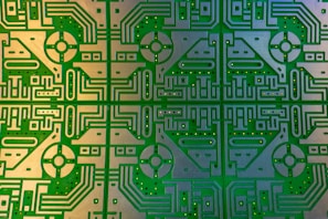 Complex and detailed circuit board featuring symmetrical patterns and intricate pathways. The design includes a repeating geometrical motif with rounded and linear elements, embedded with multiple holes for components.