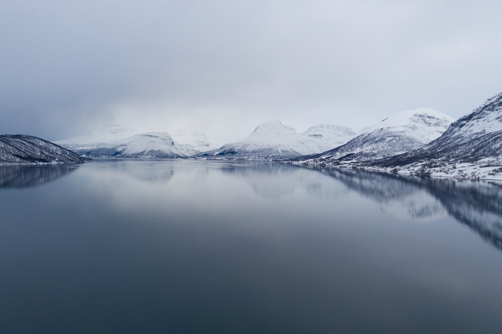 snow covered mountain near body of water during daytime