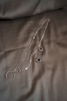 silver necklace on white textile