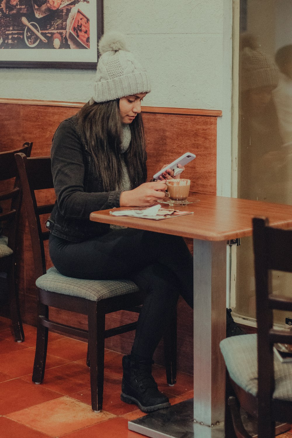 woman in black long sleeve shirt sitting on brown wooden chair