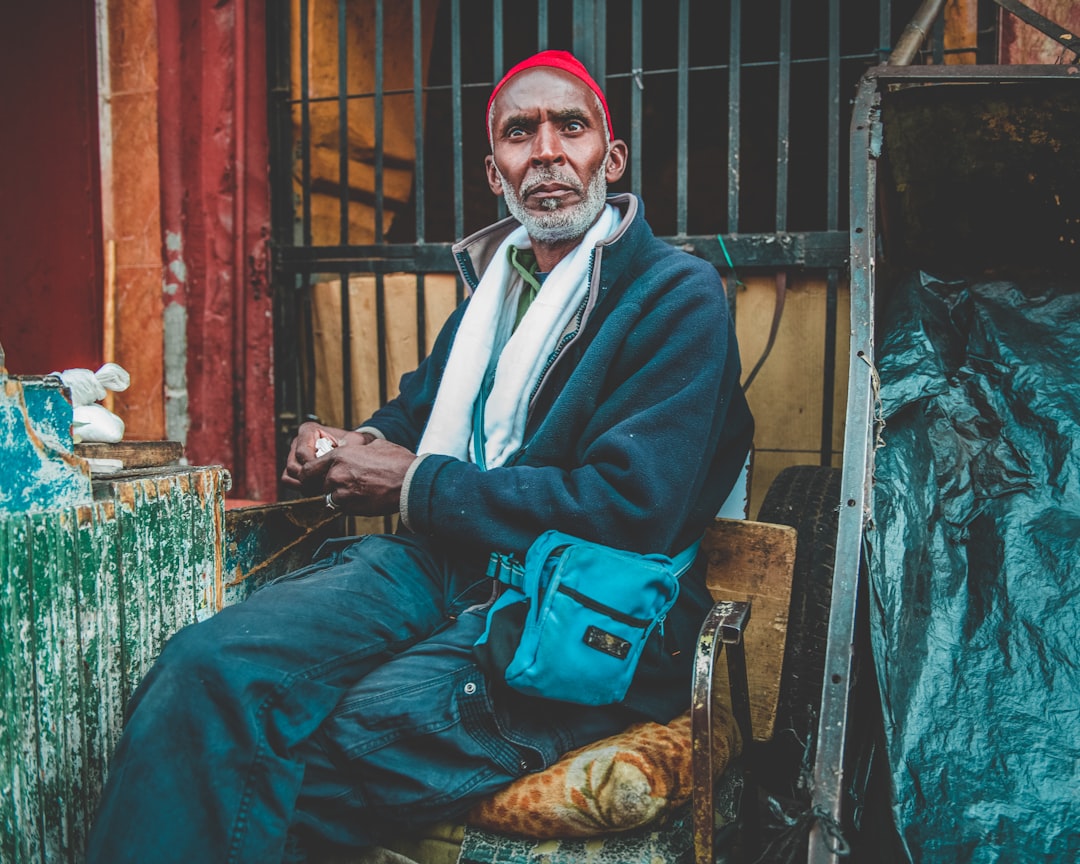 man in blue coat sitting on brown wooden chair