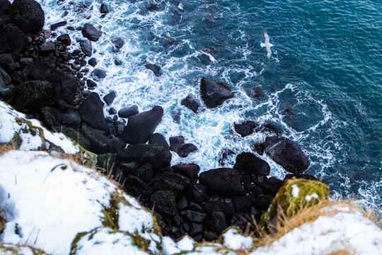 black rocks on seashore during daytime in Keflavík Iceland