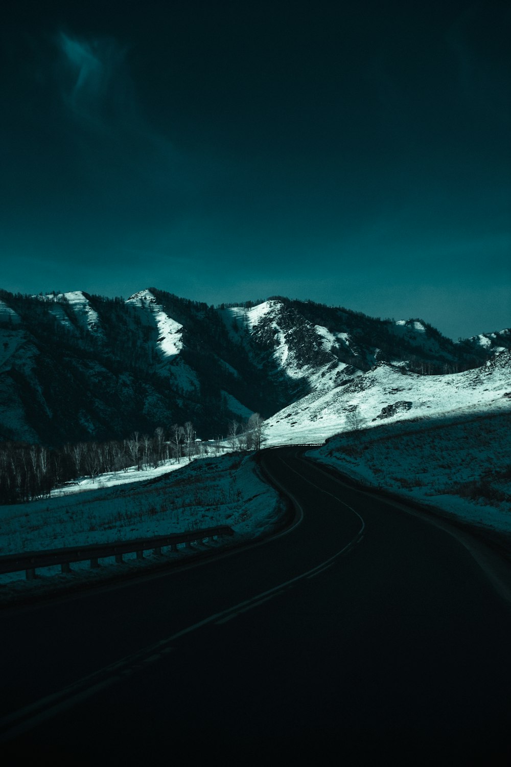 estrada cinzenta perto da montanha coberta de neve durante o dia