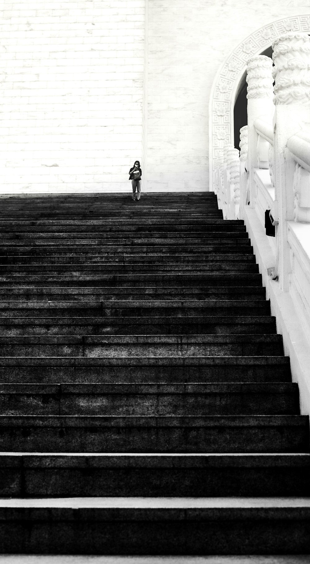 grayscale photo of person walking on wooden bridge