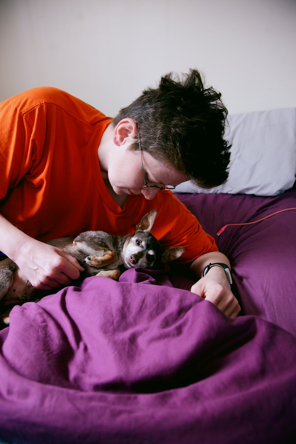 man in red crew neck t-shirt lying on bed with black and white short coated