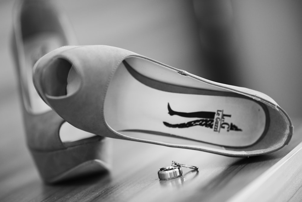 grayscale photo of white leather peep toe heeled shoes