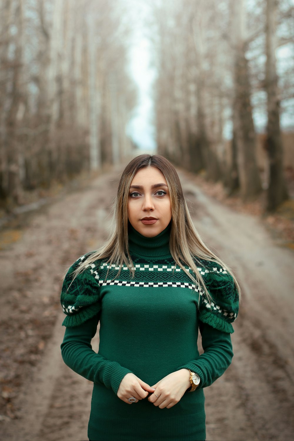 woman in green long sleeve shirt standing on dirt road during daytime