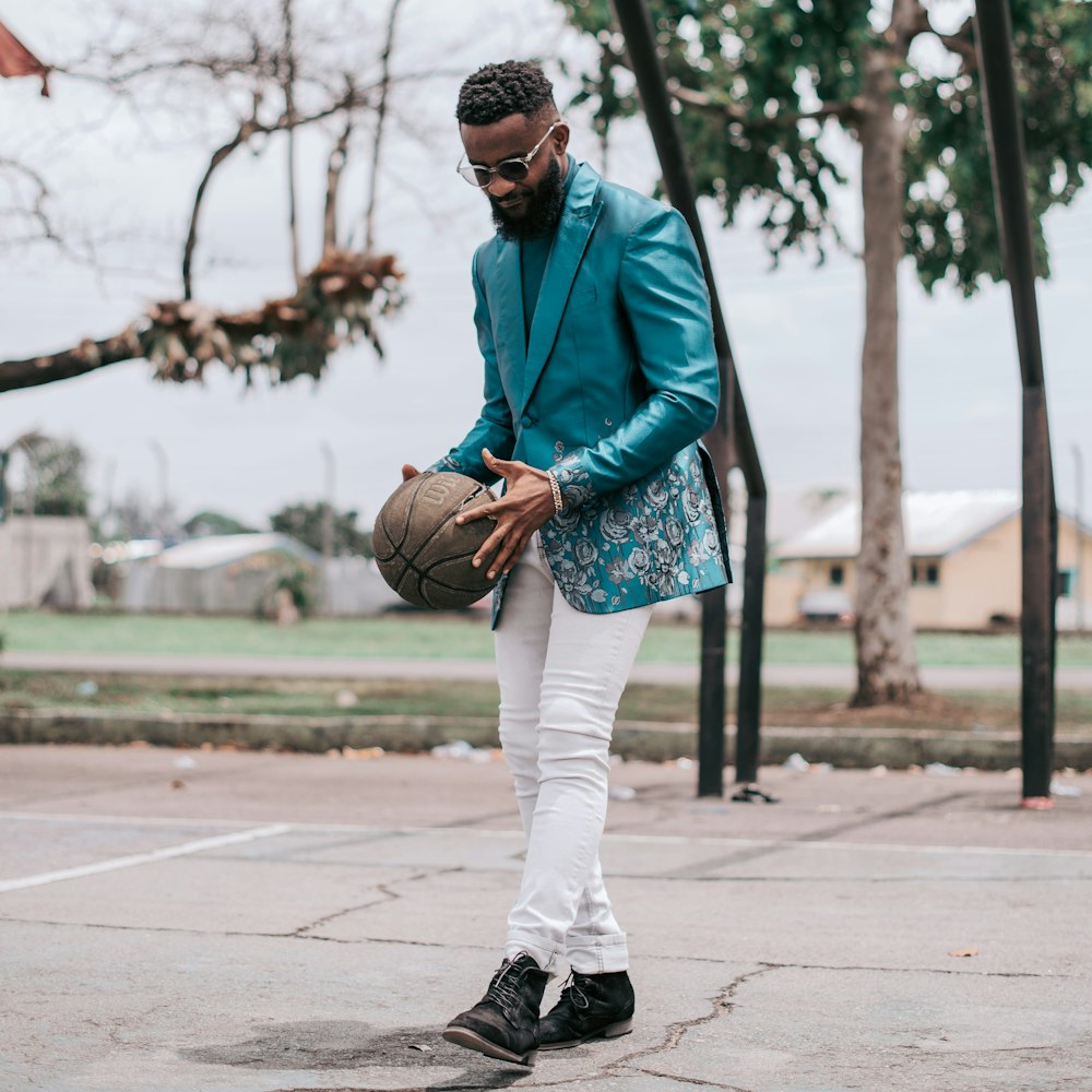 man in green jacket and white pants standing on road during daytime