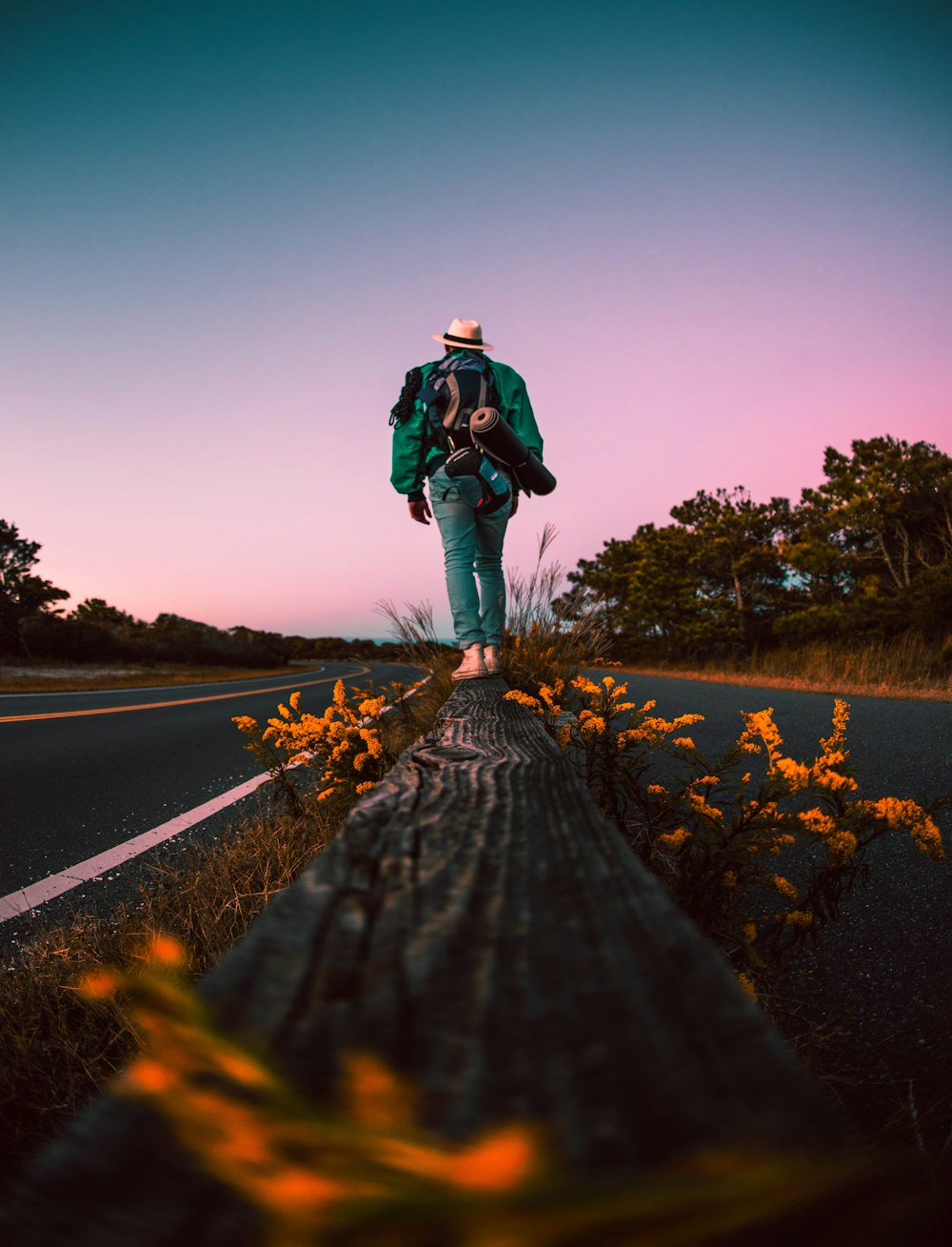 man in black jacket and blue denim jeans standing on road during daytime