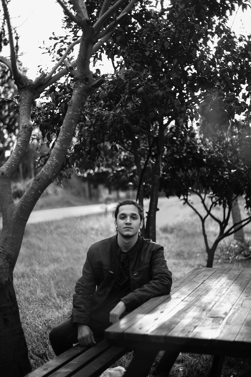 man in black jacket sitting on wooden bench