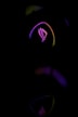 A stylized logo with a futuristic design is illuminated by neon lights in shades of pink, purple, and yellow against a dark background. The curved lines create a sense of motion and technological sophistication.