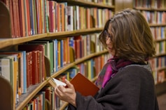 woman in red coat reading book in library