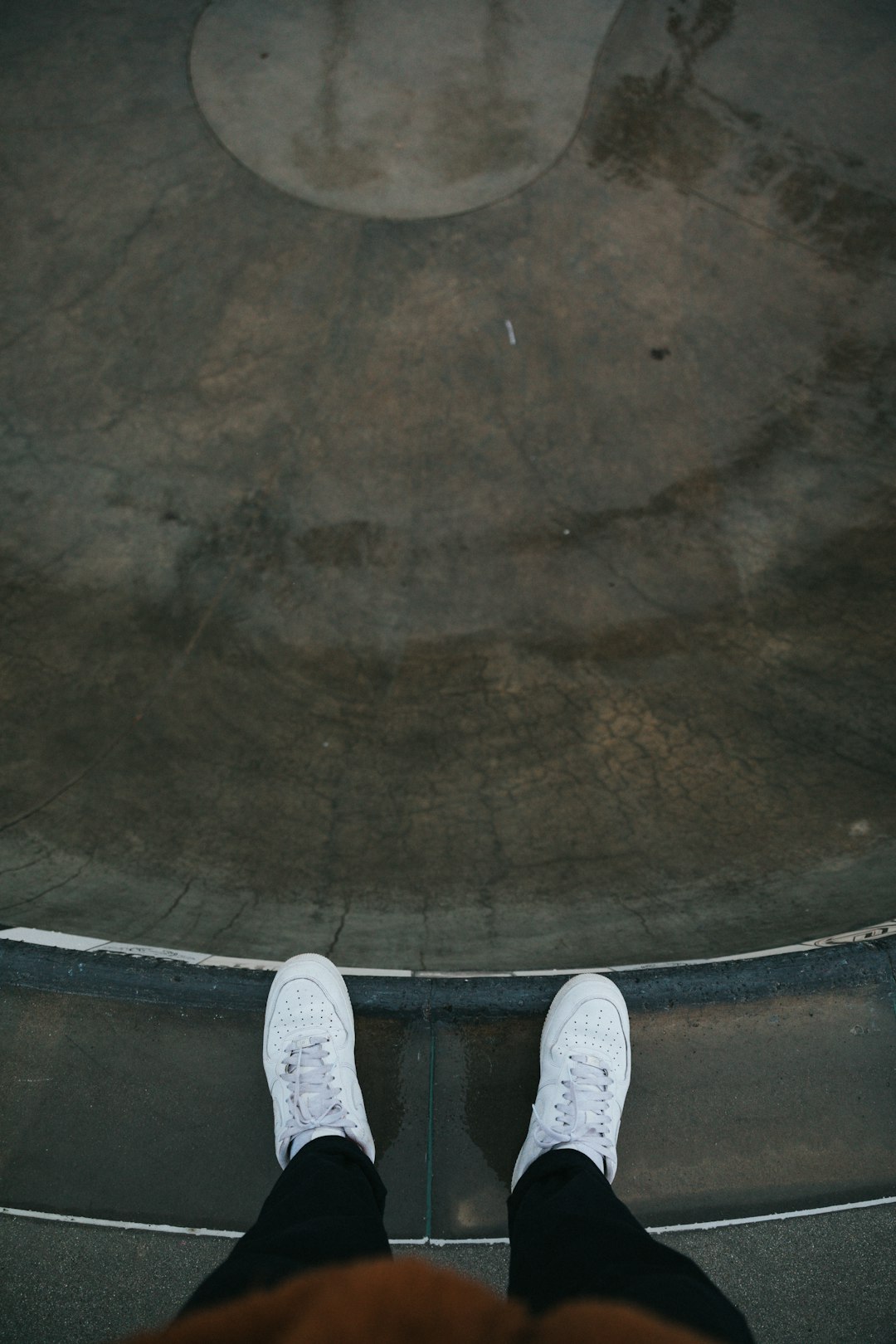 person in white sneakers standing on brown floor