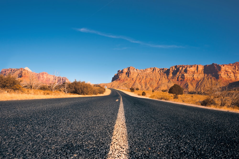 estrada de asfalto preto entre a formação rochosa marrom sob o céu azul durante o dia