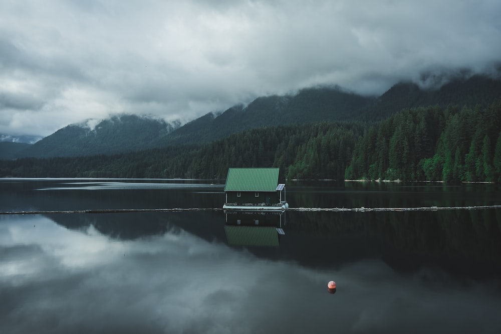 green wooden boat on lake near green trees and mountains during daytime