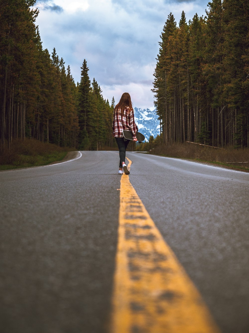 woman in black jacket walking on gray asphalt road during daytime