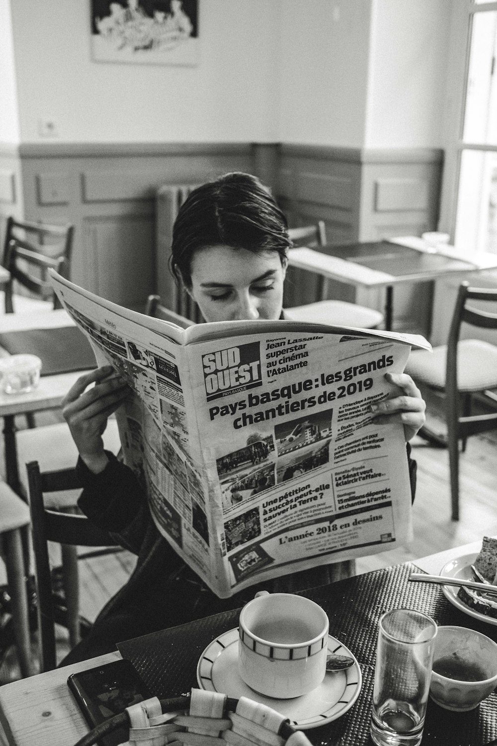 grayscale photo of man reading newspaper