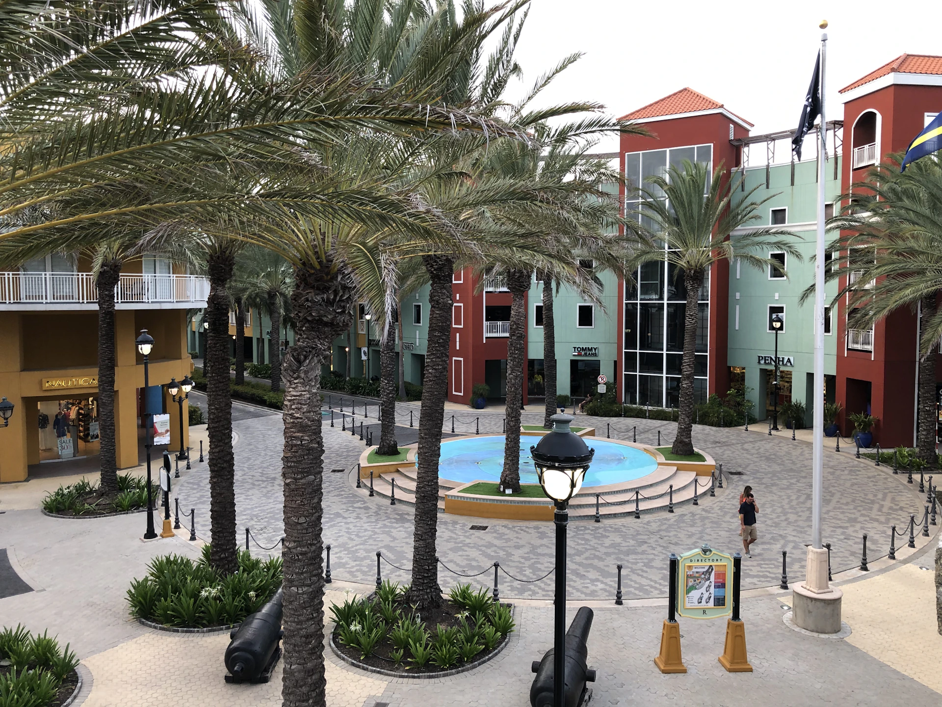 An image showcasing the colorful storefronts of various shops lining the plaza corridor, bustling with visitors.