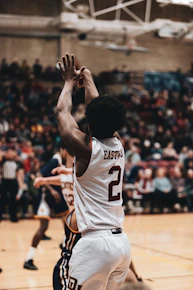 A basketball player making a jump shot with intense focus in a local league game.