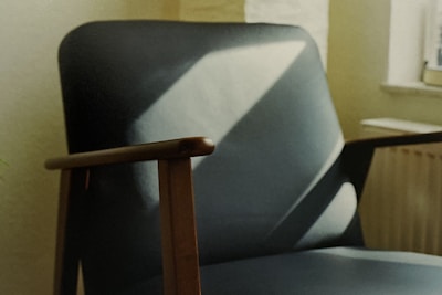 Modern wooden chair with clean lines placed in a muted, natural light setting.