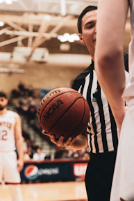 Close-up of hands holding a sports rulebook with a whistle on top.