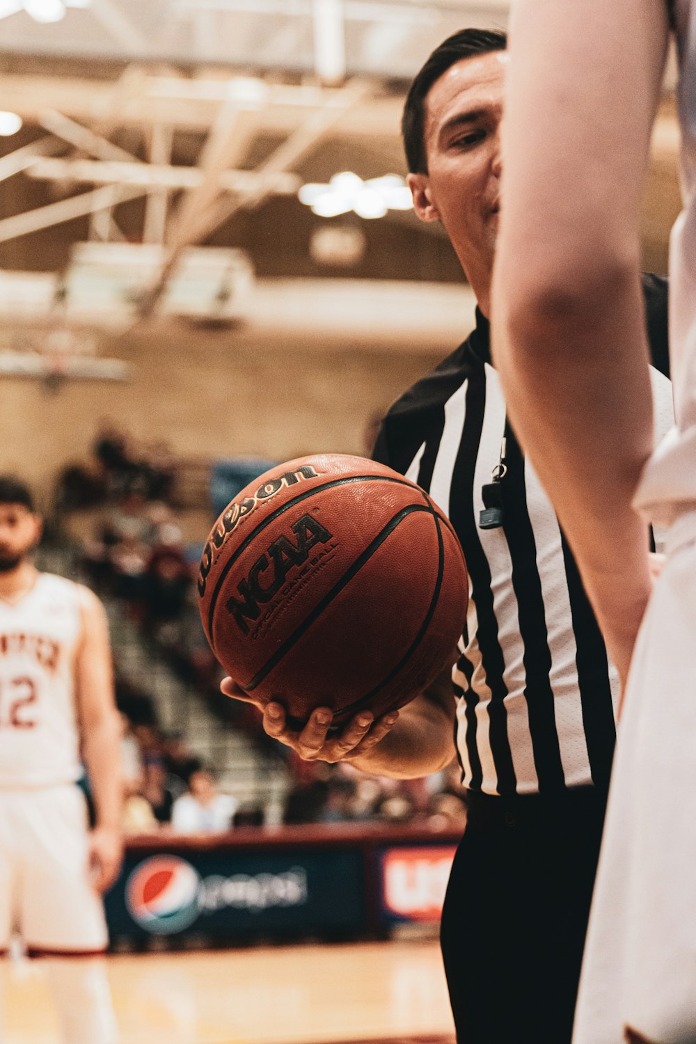 woman in white and black stripe shirt holding brown basketball