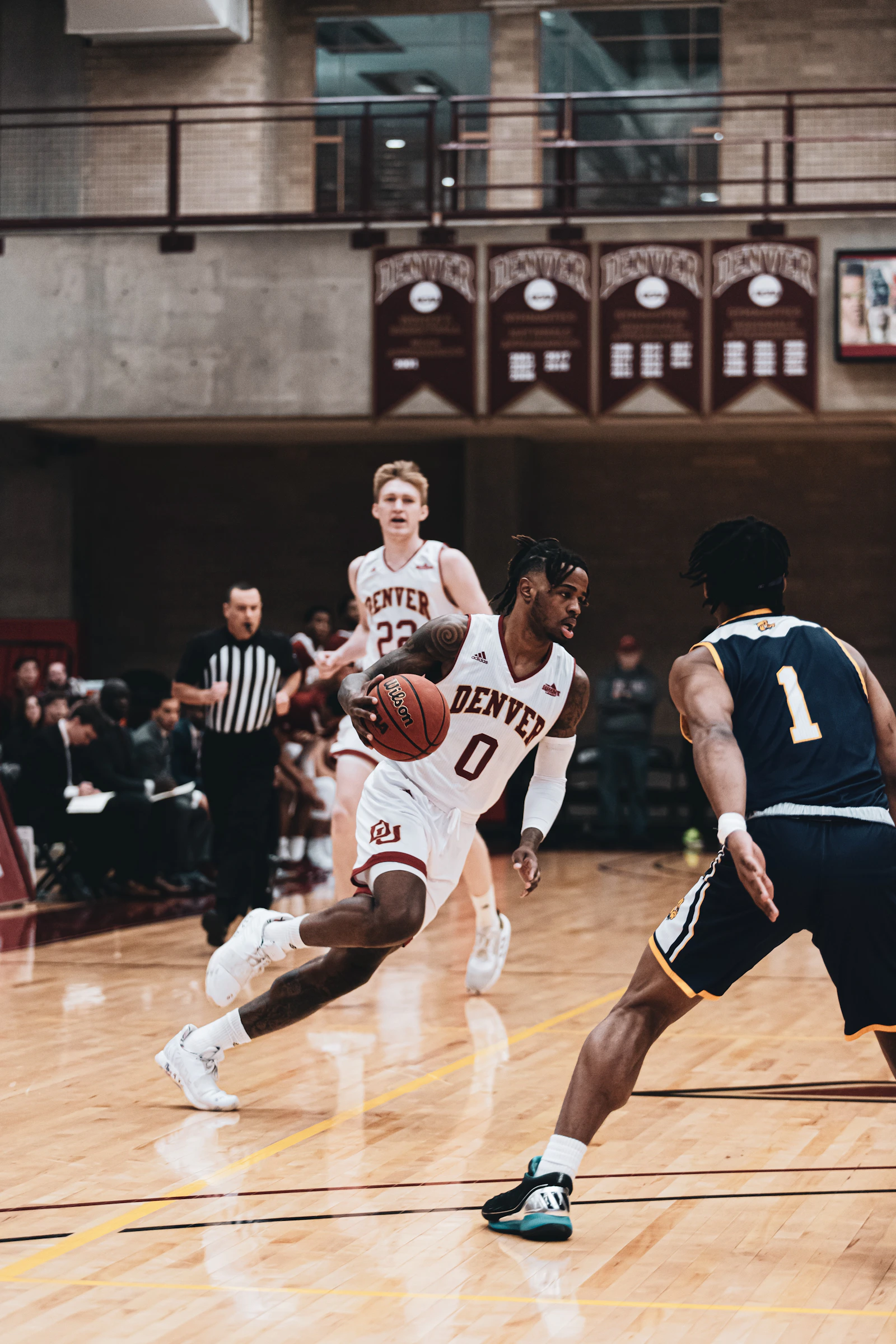Male basketball players competing on an indoor court in performance sportswear