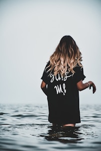 woman in black and white t-shirt standing on water during daytime