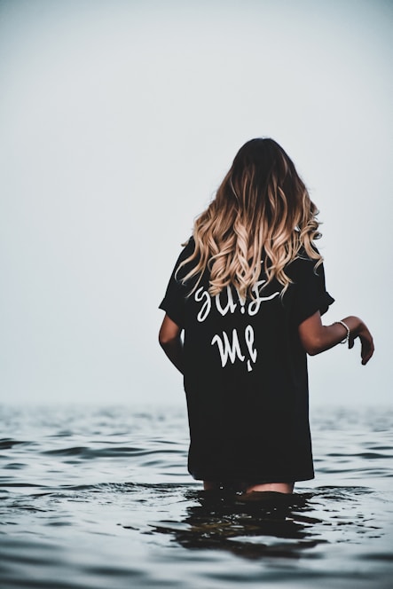 woman in black and white t-shirt standing on water during daytime