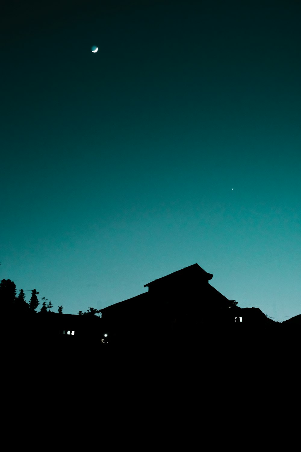 silhouette of house under blue sky during night time