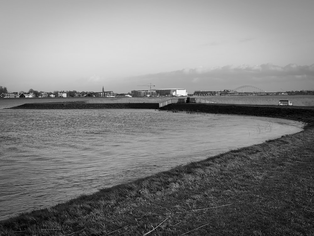 grayscale photo of body of water near bridge