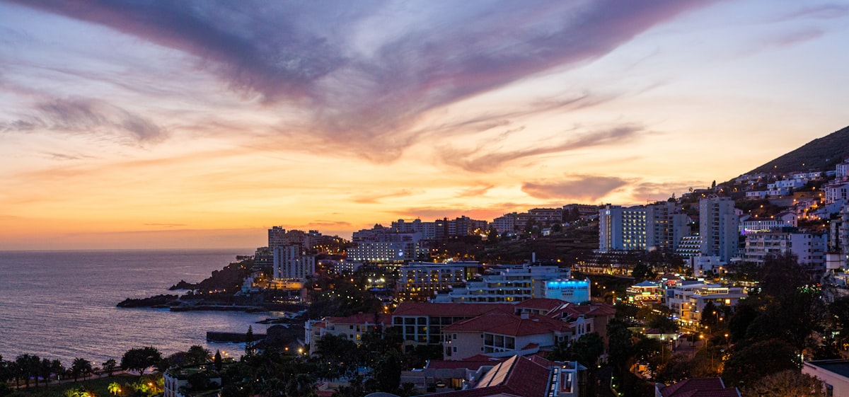 Funchal, Madeira cityscape at sunset with buildings climbing the hillside above the harbor