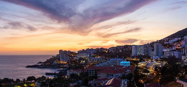 Funchal, Madeira cityscape at sunset with buildings climbing the hillside above the harbor