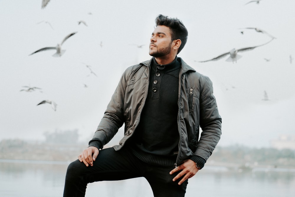 man in black leather jacket and black pants sitting on rock